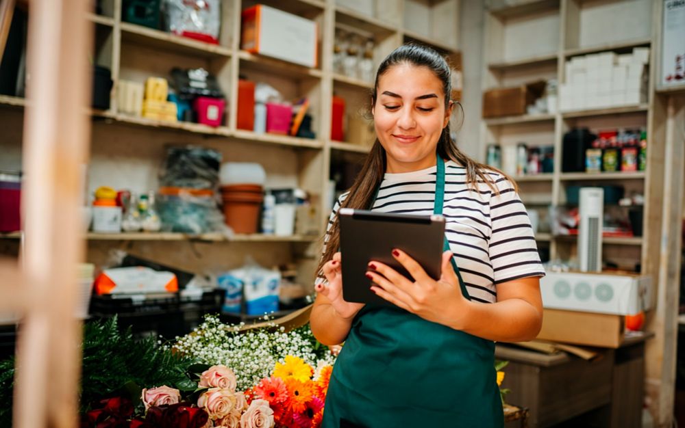 Dueña de una floristería revisando su inventario en la tableta