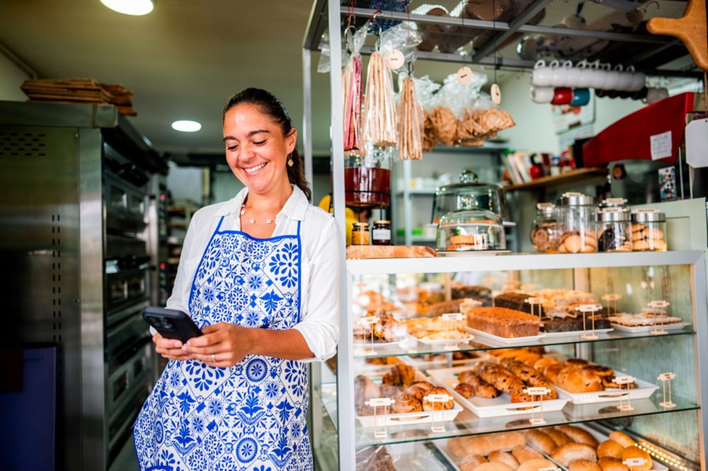 Dueña de una pastelería revisando sus ventas en el celular